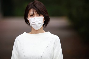 Dışarıda maske takan güzel bir Asyalı kadın.