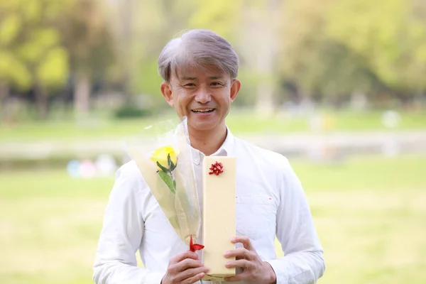 Japansk Senior Man Som Håller Gåva Med Blomma — Stockfoto