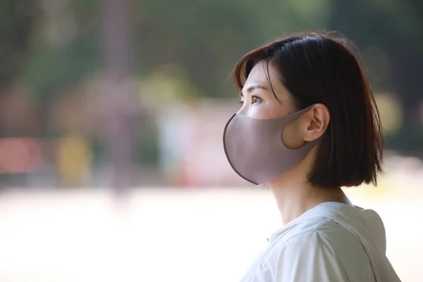 美しいアジアの若い女性がフェイスマスクを屋外で身に着けて — ストック写真