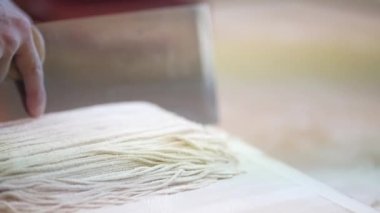 Karabuğday eriştesi hamuru kesen adama yaklaş.