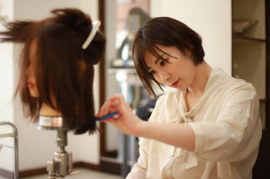 Kuaför kuaförde saç kesmeyi öğreniyor. 