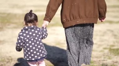 Ebeveynler ve çocuklar el ele yürüyorlar.