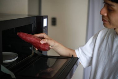 Patatesleri mikrodalgada ısıtmaya çalışan bir adam. 