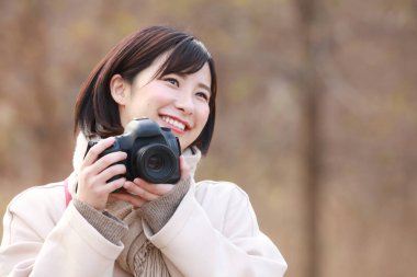 Açık havada fotoğraf çeken gülümseyen Asyalı bir kadın. 