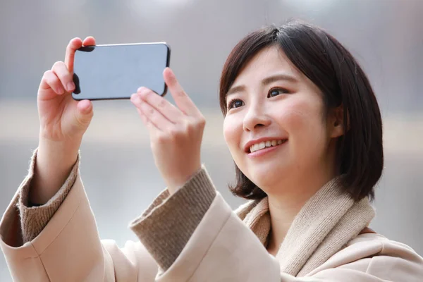 亚洲妇女在户外使用智能手机的图片 — 图库照片