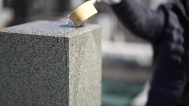 Japon mezarlığındaki mezar taşına su döken kadının yakın plan görüntüleri.