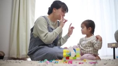 Anne, küçük kızıyla evde yerde oynuyor.