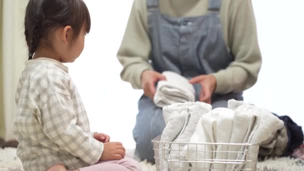 Mother Teaching Her Little Daughter Fold Clothes — Vídeo de Stock