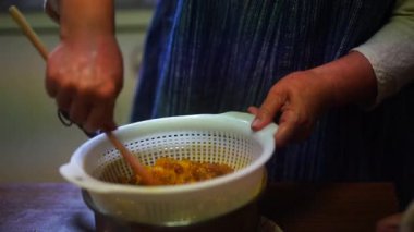 Woman rubbing boiled plums