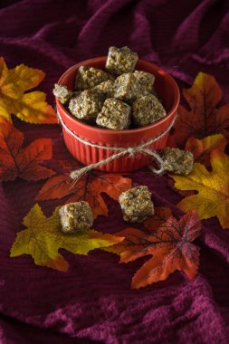 Kenevir fıstık ezmesi ısırıklarını aksanlı ve yapay yapraklı kırmızı bir kaseye koy..