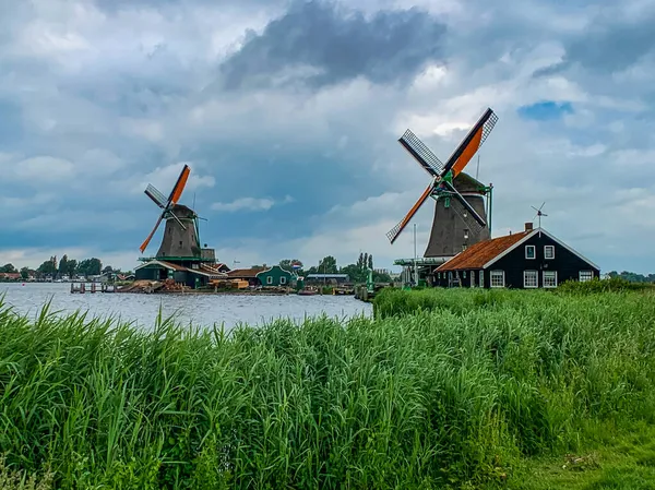 Hollanda 'da bulutlu gökyüzü ve iki yel değirmeni ve bina
