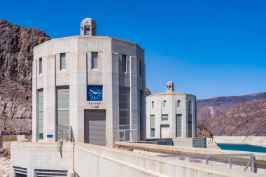 Hoover Barajı 'nın tepesinde Arizona-Nevada sınırında saatli binalar.