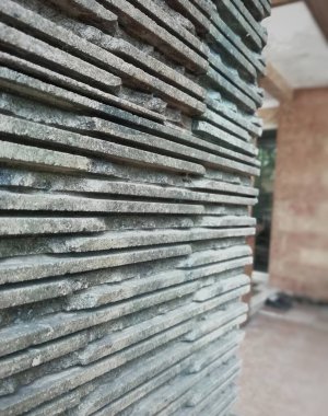 Taş, çimento, kum vs. karışımından oluşan soyut duvar teras duvarına kazınmış ve dikilmiş. 