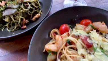 Kırmızı şarap, siyah tabakta İtalyan makarnasının yanındaki bardağa dökülür.