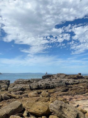 açık mavi gökyüzünün altında kayalar ve deniz