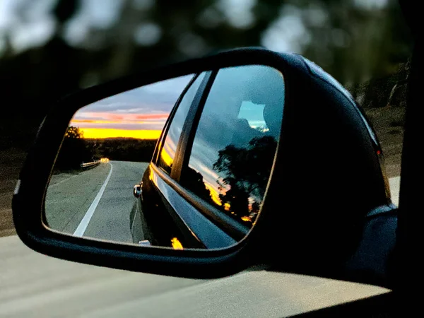 Puesta de sol reflejada en el retrovisor de un coche — Foto de Stock