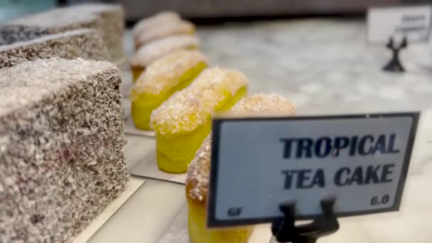 Pasteles frescos y pasteles se venden en un escaparate detrás de un vaso en un café, primer plano — Vídeo de stock