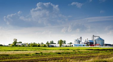 steel grain tanks are located near the field. Agricultural facilities for storage and drying of grain