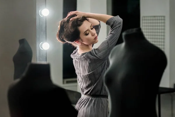 穿着时髦西服的年轻女模特站在镜子前的办公室里 一副模特儿的样子 — 图库照片