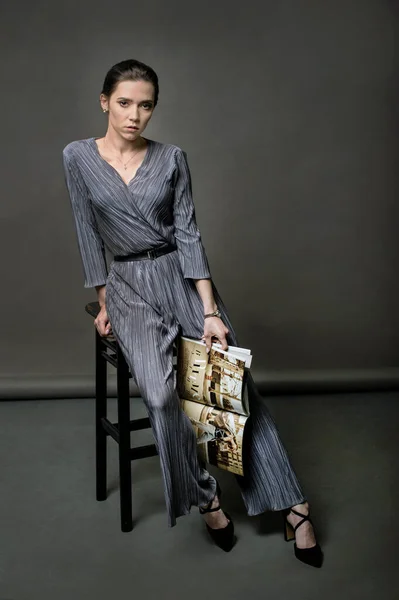 穿着时髦西服的时髦姑娘手里拿着一本光彩夺目的杂志 — 图库照片