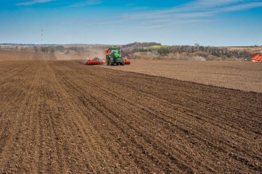 BAYKIVTSI, TERNOPIL REGION, UKRAINE - 10 Nisan 2021: Çiftçiler, ekili bir tarlada ekiciyle John Deere 8370R traktörü kullanarak gübre uygulayın