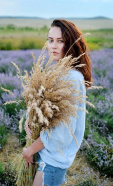 Büyük bir buket kurutulmuş çiçek, sarı sazlıklar, bir kızı lavanta tarlasında tutmak.