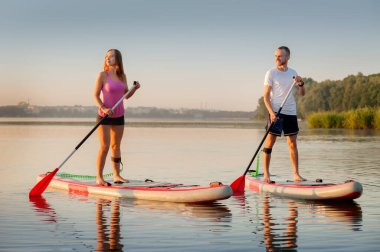 A couple swims together on a stand-up paddleboard, active lovers' recreation, water tourism