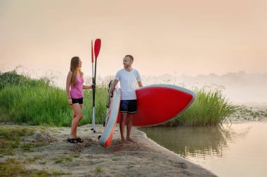 preparing to swim on a stand-up paddle board, active recreation of lovers, tourism on the water