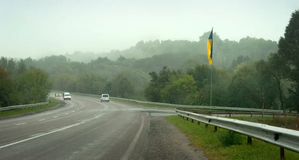 Droga Asfaltowa Deszczowy Dzień Mgliste Wzgórza Słup Ukraińską Flagą — Zdjęcie stockowe