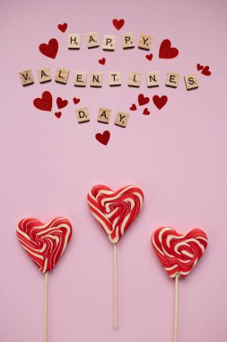 Happy valentines day with heart shaped candies, pink background