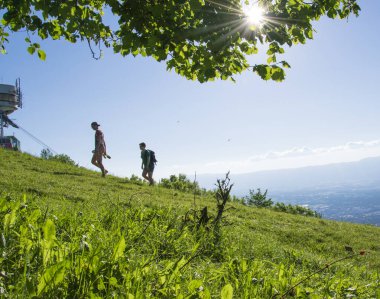 Arkadaşlar yeşil bir uçurum ve güneşli bir manzarayla İsviçre 'de yürüyüş yapıyorlar..