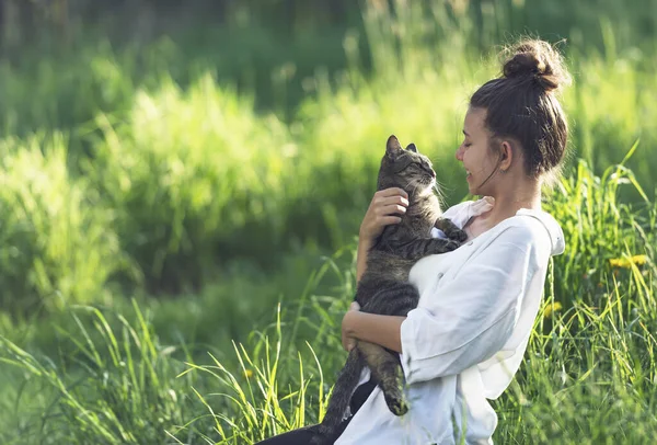 照片中的是一个手里拿着一只胖胖的猫的女孩 猫与女孩相互凝视着对方的眼睛 可以看出他们之间有一种友好关系 那女孩嘲笑那只猫 — 图库照片