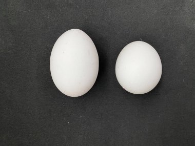 Siyah arkaplanda beyaz küçük ve büyük yumurtalar