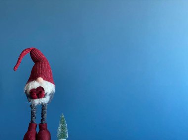 Yılbaşı kartı, yeni yıl ağacı ve mavi arka planda sevimli bir cüce.