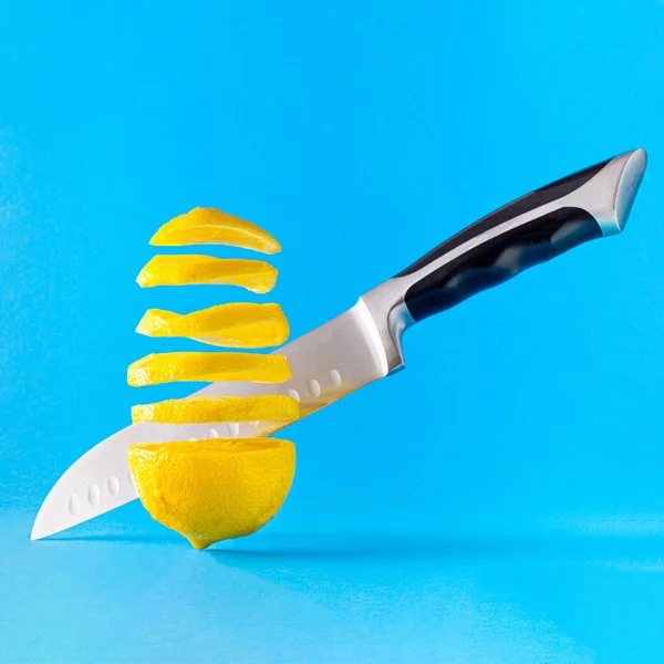在蓝色背景下 切碎漂浮的新鲜柠檬和小刀 最低限度概念概念 图库图片