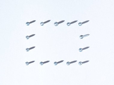 Metal vidalardan yapılmış çerçeve, beyazmok arka planına karşı fotokopi alanı ve güneş ışığının gölgesinden oluşuyor. Minimum düz kompozisyon. Yaratıcı inşaat aracı fikri.