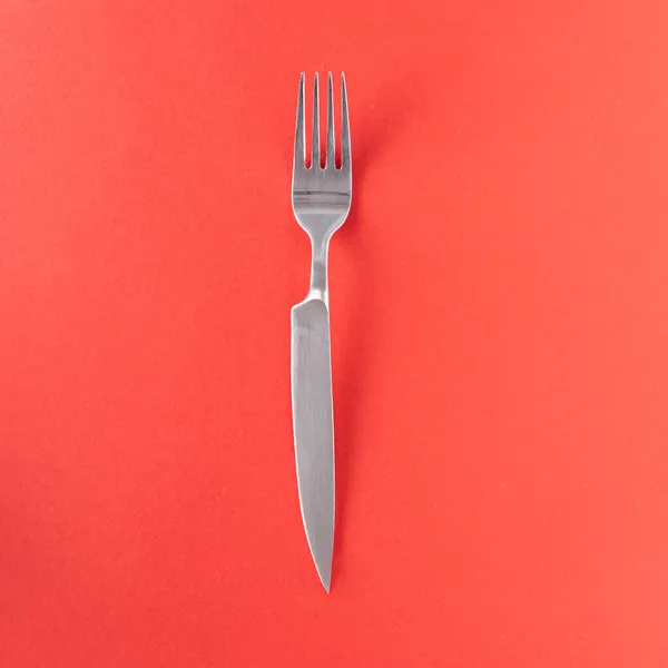 叉具锋利的刀柄与红色背景 创意双刀的想法 最小平铺构图 免版税图库图片
