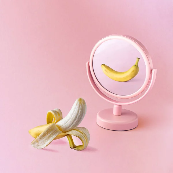 镜像反射 新鲜的黄色香蕉映衬着粉红的背景 切碎的水果 最低限度概念 图库照片