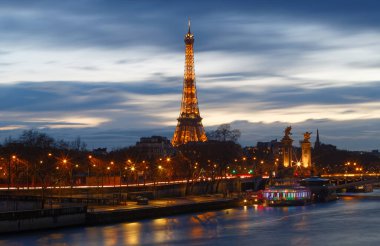 PARIS, FRANCE - 11 Mart 2022: Eiffel Kulesi gece aydınlandı. Paris, Fransa 'daki Seine nehrinin kıyısında bulunan mühendis Gustave Eiffel' in adını verdiği dövmeli demir kafes kulesi..