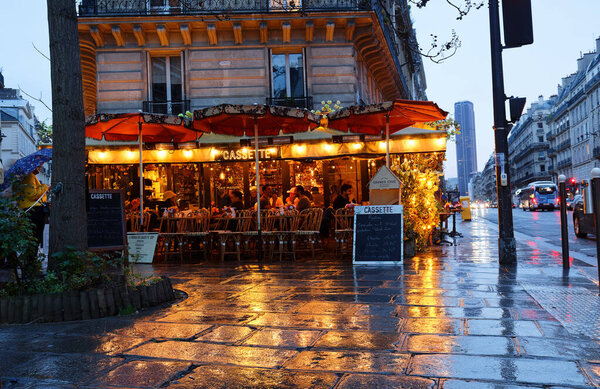 Paris, France-March 13 , 2022 : The traditional French cafe Cassette at rainy night . It located in Montparnasse district in Paris, France.