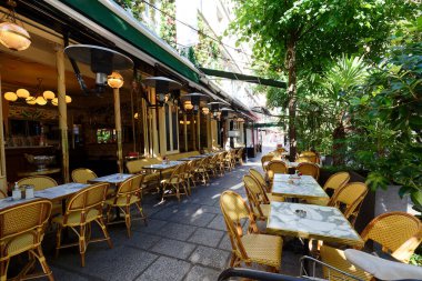 Cosy street with round tables and bright chairs of traditional outdoor French cafe in Paris. France.