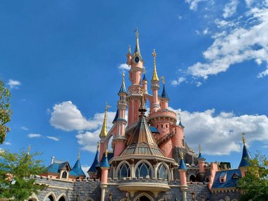 The fairytale castle in park on cloudy background.