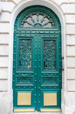 The rich decor decorates an entrance door of the old building of traditional architecture of in downtown, Paris, France.
