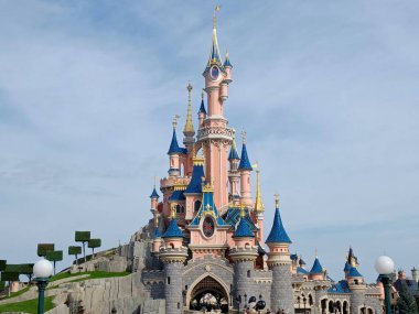 The fairytale castle in park on cloudy background.