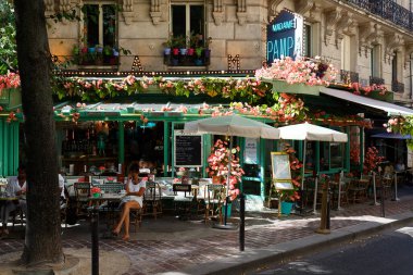 Paris, France - August 03, 2022 : Cafe Madame Pampa decorated with flowers in the Montparnasse Quarter near the Gare Montparnasse, Montparnasse Tower.