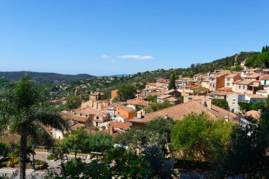 High side view beautiful village in south of France, Bormes les Mimosa village with many house in deferent level, orange roof with background clouds and blue sky.