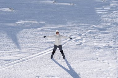 mujer atractiva con gorro y abrigo blanco en estacion de esqui en una montaa nevada