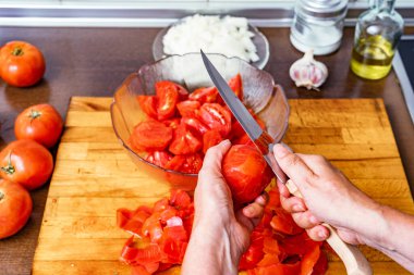 Persona pelando y cortando tomates rojos en la cocina para hacer tomate frito, gazpacho ensalada, con aceite y sal