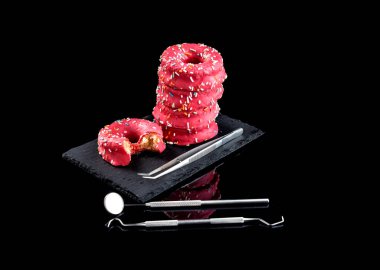 İlk plano de columna de donuts rosas encima de un plato ayık fondo negro ve enstrümantal medio dişçi