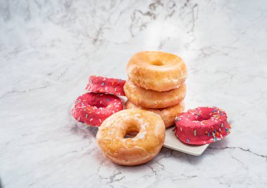 İlk plano de donuts de azucar y donuts rosas sobre una mesa blanca